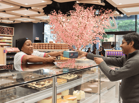 A smiling Westham Bakery staff member serves a customer across the counter at the new Overport store.